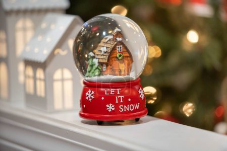 Foto de Una pequeña bola de nieve navideña con un texto "Let it snow" sobre el fondo borroso - Imagen libre de derechos