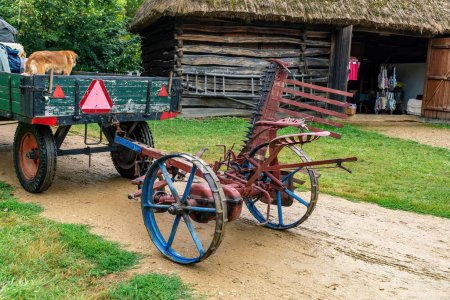 Téléchargez les photos : Plan rapproché d'une tondeuse d'époque tirée par une calèche tirée par des chevaux dans la cour herbeuse et boueuse d'un musée en plein air en République tchèque - en image libre de droit