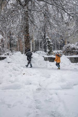 Téléchargez les photos : Deux enfants marchent dehors dans la tempête de neige - magie hivernale - en image libre de droit