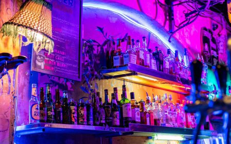 Foto de Un primer plano de bebidas alcohólicas en botellas en un colorido bar con luces de neón - Imagen libre de derechos