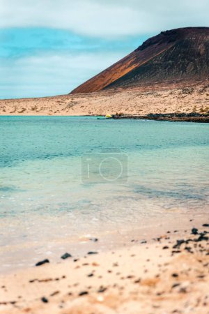 Foto de Un plano vertical del hermoso océano con la montaña al fondo en la isla de La Graciosa - Imagen libre de derechos