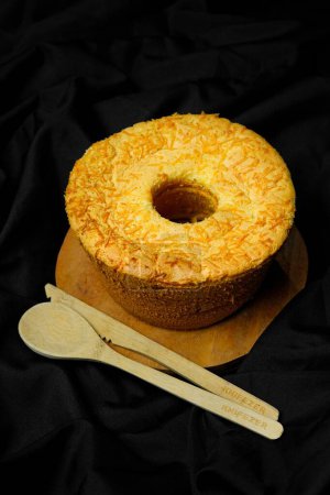 Téléchargez les photos : Une vue verticale du gâteau en mousseline de soie sur panneau en bois et des couverts en bois sur fond satiné noir - en image libre de droit