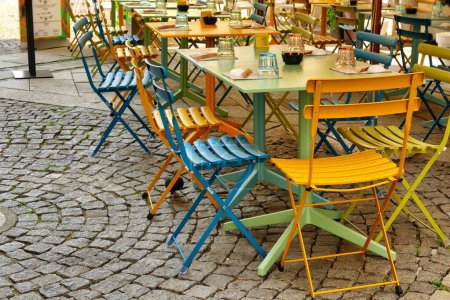 Foto de El chais colorido vacío y mesas en un café al aire libre en una acera - Imagen libre de derechos