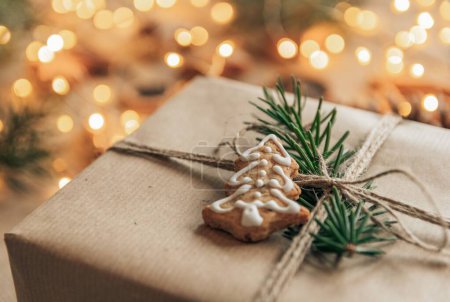 Foto de Foto de cerca de galleta de jengibre en forma de corazón en Navidad presente delante de las luces bokeh. Regalo de Navidad envuelto en papel marrón y decorar - Imagen libre de derechos