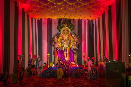 Téléchargez les photos : L'idole du Seigneur Ganesha dans la salle d'adoration avec la lumière rouge néon, et entouré de petites idoles, au festival Hindi Ganpati à Mumbai, Inde - en image libre de droit