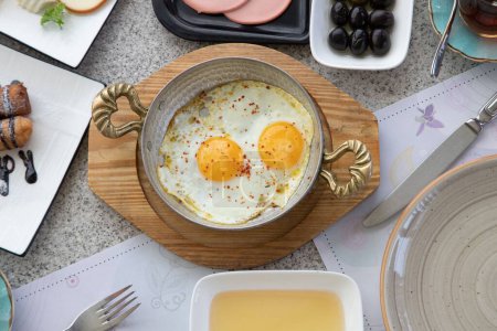 Photo for A high angle shot of a decorative pot with gourmet fried eggs on a breakfast table - Royalty Free Image