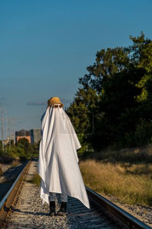 Téléchargez les photos : Un fantôme debout sur les voies ferrées à la campagne - concept Halloween - en image libre de droit