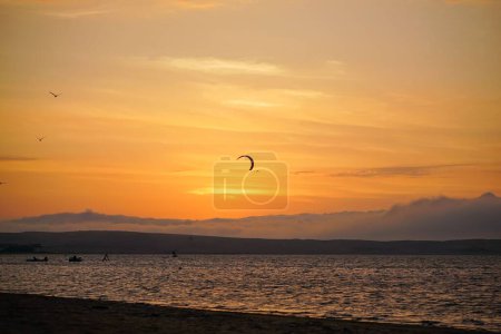 Téléchargez les photos : Un beau cliché d'une personne faisant du kitesurf sur une mer sous un ciel orangé couchant - en image libre de droit