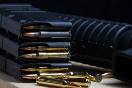 Foto de Varias balas de 223 rifles en un cargador colocado delante de un rifle AR-15 - Imagen libre de derechos