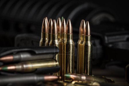 Photo for Various 223 rifle bullets standing or laying next to a full AR-15 magazine full of ammo - Royalty Free Image
