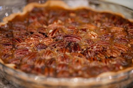 Photo for A homemade baked pecan pie in transparent glass serving plate with blur background - Royalty Free Image