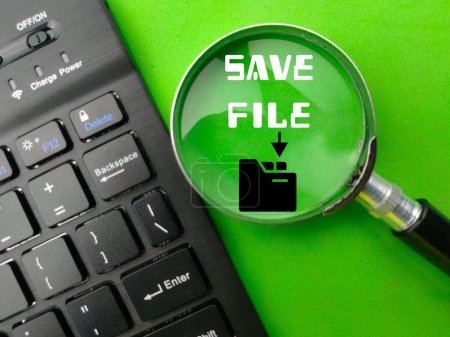 Photo for Top view wireless keyboard and magnifying glass with the word SAVE FILE on green background.Business concept. - Royalty Free Image