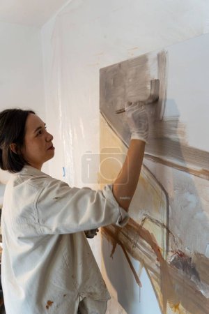 Photo for A vertical shot of a young female artist working on art in her studio - Royalty Free Image