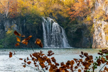 Foto de Una toma de otoño de una cascada que desciende a un lago rodeado de naranjos, Croacia - Imagen libre de derechos