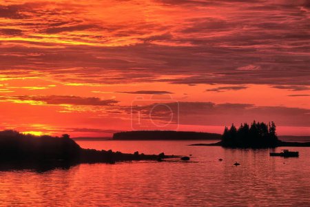 Foto de Colorida escena costera de Maine. Brillante amanecer sobre Penobscot Bay, pintando cielo dramático y nubes tonos vibrantes de rojo, naranja y amarillo. - Imagen libre de derechos