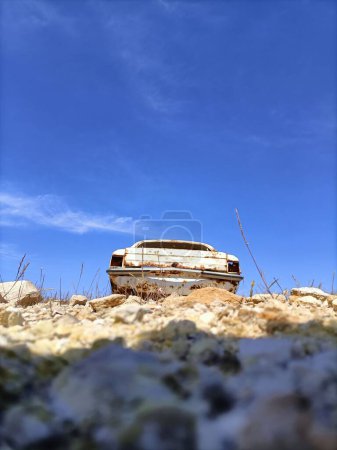 Foto de Un plano vertical de bajo ángulo de un viejo coche oxidado abandonado en medio de un campo - Imagen libre de derechos