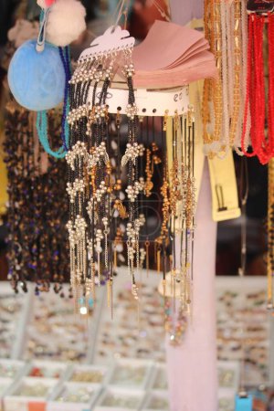 Foto de Una pantalla vertical de joyería en un mercado de pulgas, colgada de cuerdas - concepto de accesorios - Imagen libre de derechos