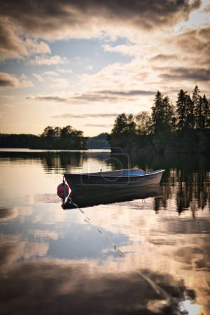 Téléchargez les photos : Plan vertical d'un bateau stationné dans un lac au coucher du soleil - en image libre de droit