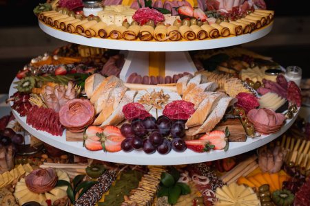 Téléchargez les photos : Gros plan d'une planche de charcuterie gastronomique avec salami, fromage et fruits décoratifs - en image libre de droit