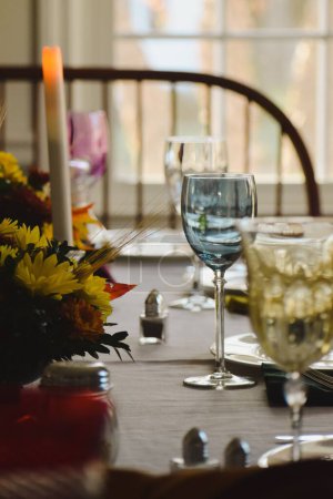 Foto de Una toma vertical de copas de vidrio junto con velas y flores en una mesa de madera - Imagen libre de derechos