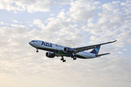 Foto de Una toma de bajo ángulo de un avión Airbus A330-941 de la aerolínea Azul Linhas, volando al amanecer, con nubes en el fondo - Imagen libre de derechos