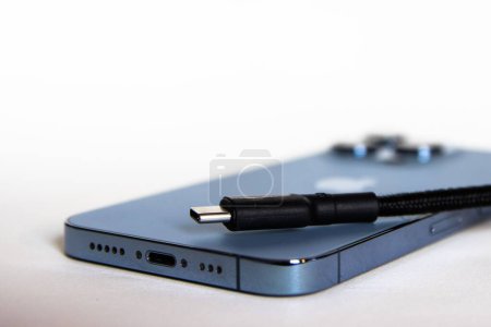 Foto de Un primer plano de un iPhone 13 Pro azul con un cable USB - Imagen libre de derechos