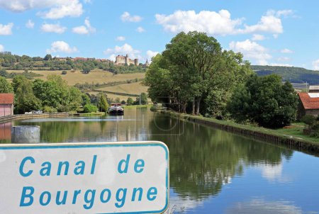 Foto de Canal de Borgoña detrás de la placa del canal, en Vandenesse en Auxois, Francia. En una colina el castillo de Chateauneuf - Imagen libre de derechos