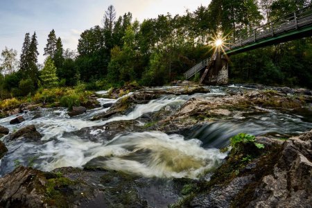 Foto de Un pintoresco plano de una pasarela a través de un río rocoso con efecto sedoso - Imagen libre de derechos