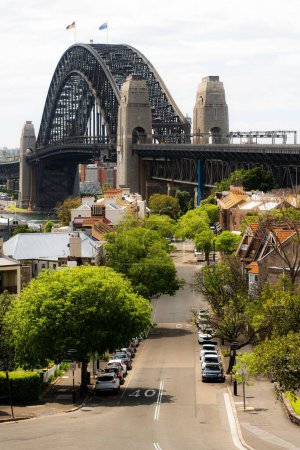 Photo for A vertical view of buildings before the Sydney Harbour bridge on a cloudy day - Royalty Free Image
