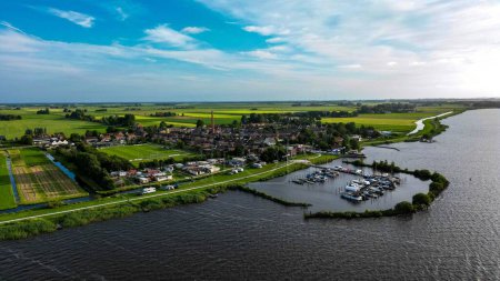 Téléchargez les photos : Vue aérienne du vieux village d'Oosterzee aux Pays-Bas sur la rive d'un lac par une journée ensoleillée - en image libre de droit