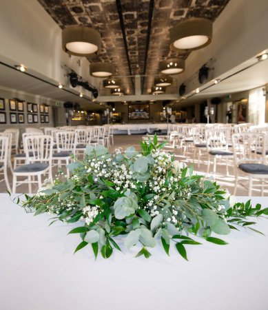 Téléchargez les photos : Un gros plan des fleurs blanches sur une table dans un lieu de mariage vide - en image libre de droit