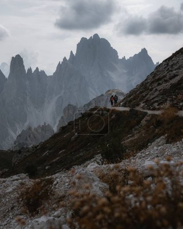 Téléchargez les photos : Un plan vertical de deux personnes en randonnée dans les Dolomites italiennes sous le ciel nuageux - en image libre de droit