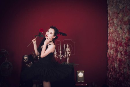 Photo for A studio shot of an East Asian female model wearing a black mini dress and holding a rose - Royalty Free Image