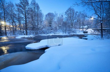 Téléchargez les photos : Paysage hivernal avec rivière traversant une forêt enneigée, longue exposition - en image libre de droit