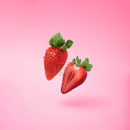 Foto de Una representación 3D de fresa fresca cortada flotando en el aire sobre el fondo rosa - Imagen libre de derechos