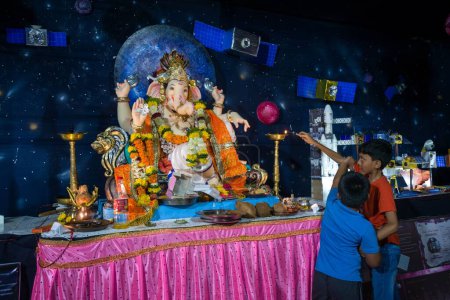 Foto de Dos chicos de pie frente al ídolo del Señor Ganesha en el festival Ganpati en Mumbai en la India - Imagen libre de derechos