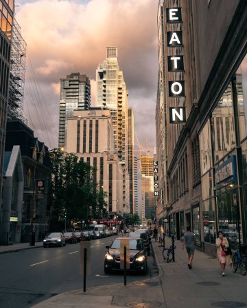 Photo for A vertical shot of street with cars, walking people and modern architectures at Sunset in Eaton Center Montreal, Canada - Royalty Free Image