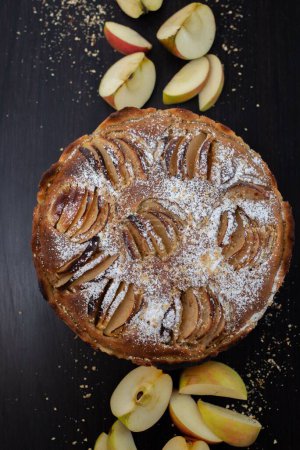 Téléchargez les photos : Vue verticale d'une tarte aux pommes avec du sucre en poudre sur fond noir - en image libre de droit