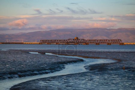 Téléchargez les photos : Vue panoramique d'une rivière menant à un plan d'eau plus grand avec un pont traversant - en image libre de droit