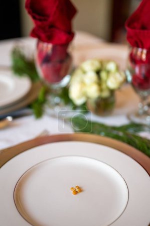 Foto de Un disparo vertical de una pequeña cantidad de grano de maíz en un plato vacío sobre la mesa en el fondo borroso - Imagen libre de derechos