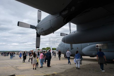 Photo for A group of visitors walking around a Lockheed C-130 Hercules aircraft at an air show - Royalty Free Image