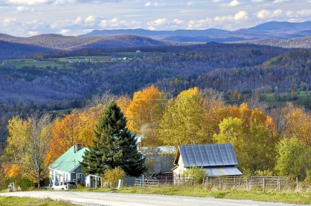 Téléchargez les photos : Route de campagne tranquille dans le nord-est du Royaume du Vermont rural avec vue imprenable sur les montagnes, les bâtiments agricoles et le feuillage d'automne coloré. - en image libre de droit