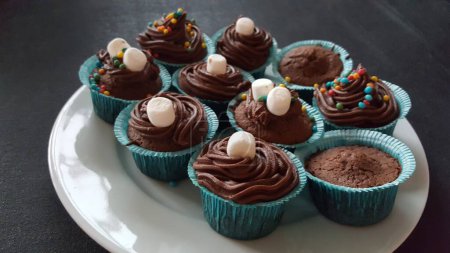 Foto de Un primer plano de deliciosos cupcakes con glaseado de chocolate en un plato sobre la mesa - Imagen libre de derechos
