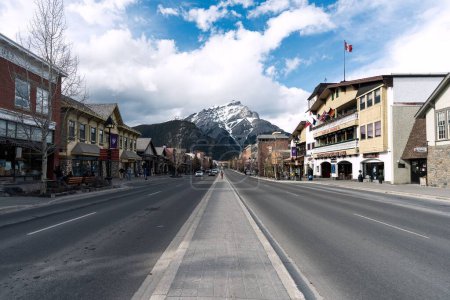 Téléchargez les photos : La rue Banff Avenue est entourée de bâtiments avec les Rocheuses canadiennes en arrière-plan - en image libre de droit