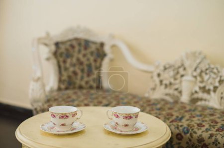 Photo for The interior of an elegant room decorated with a vintage couch in front of two elaborate teacups - Royalty Free Image