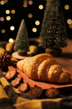 Foto de Un tiro vertical de un croissant con decoraciones de mesa de Navidad en el fondo - Imagen libre de derechos