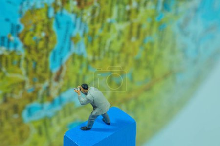 Téléchargez les photos : Un photographe prend une photo du globe, figurines miniatures scène - en image libre de droit
