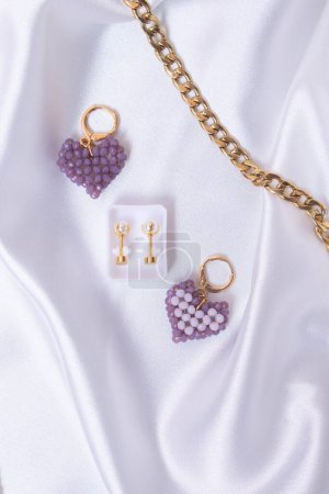 Téléchargez les photos : Un gros plan de coeur en forme de porte-clés perlé avec une paire de boucles d'oreilles et une chaîne en or - en image libre de droit
