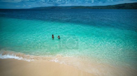 Photo for The aerial view of a couple swimming in the blue sea by the shore of Samana island - Royalty Free Image