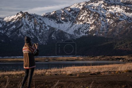 Téléchargez les photos : Une jeune femme photographiant la montagne enneigée dans les hautes terres - en image libre de droit